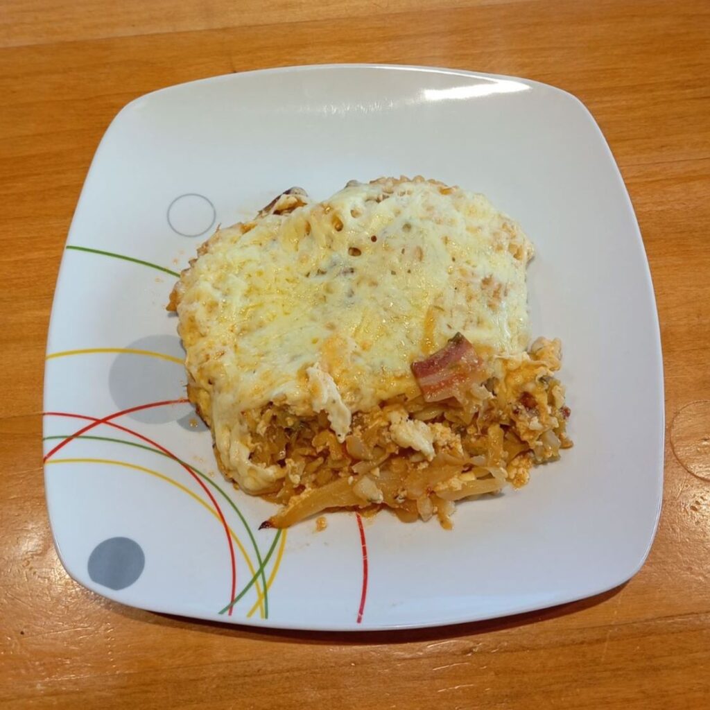 Neatly served square portion of Creamy Cabbage Pasta Bake on a flat plate, showing pasta, cabbage, and melted cheese combined.