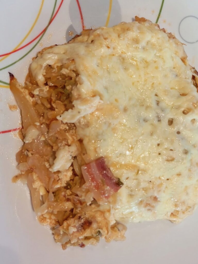 Close-up of a square slice of Creamy Cabbage Pasta Bake served on a flat plate with visible pasta, cabbage, and melted cheese.
