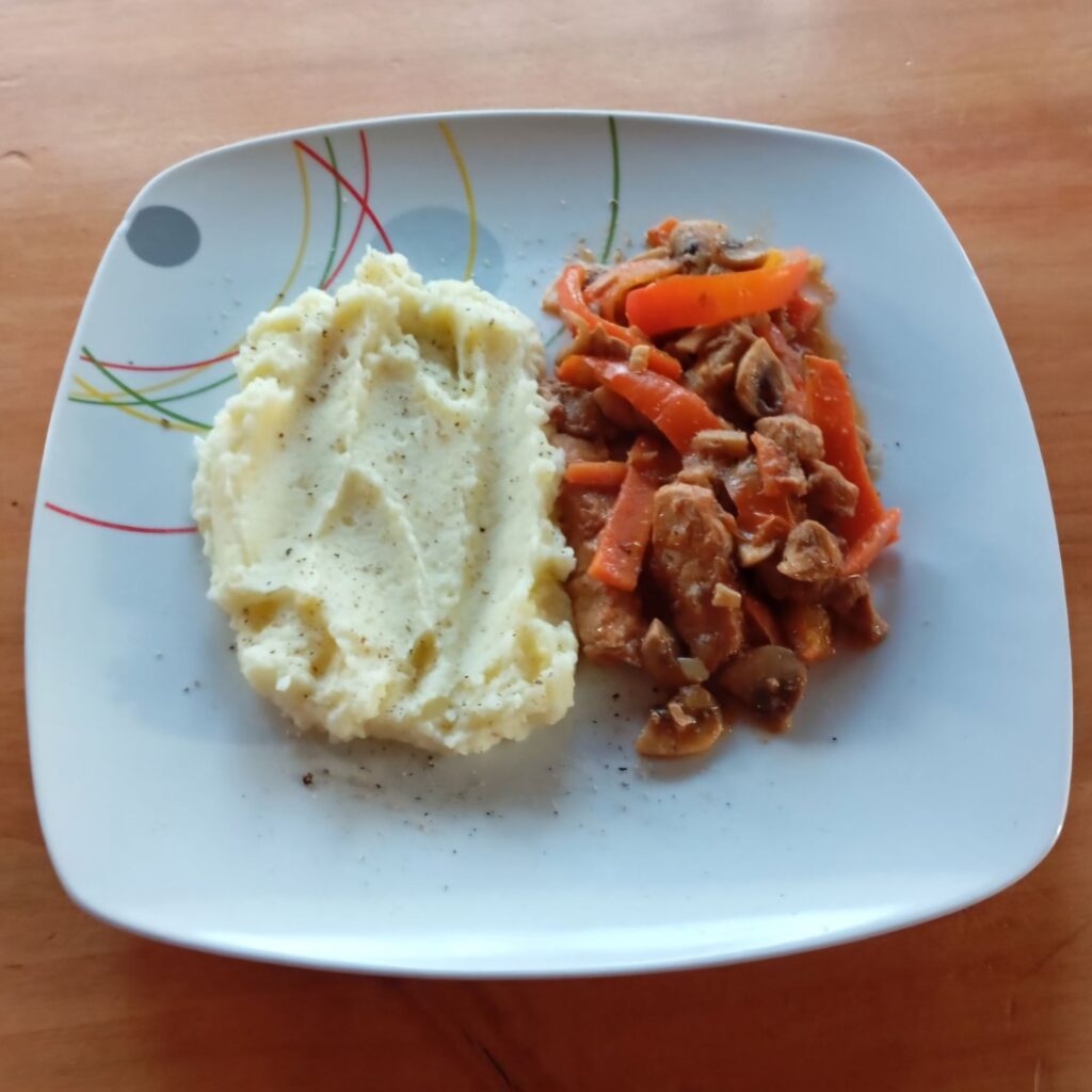 Braised Pork Vegetables Dish served on a plate with braised pork, mushrooms, and vegetables alongside creamy mashed potatoes topped with ground black pepper.