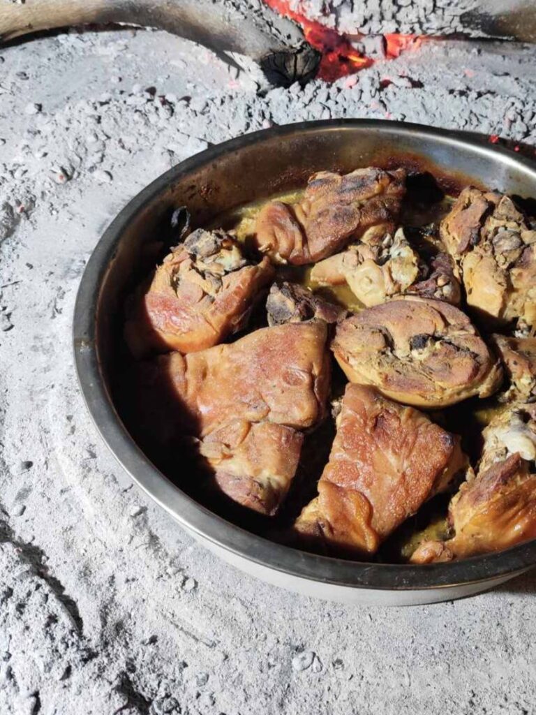 Suckling Pig Peka Style roasted in a round pan with golden meat pieces.