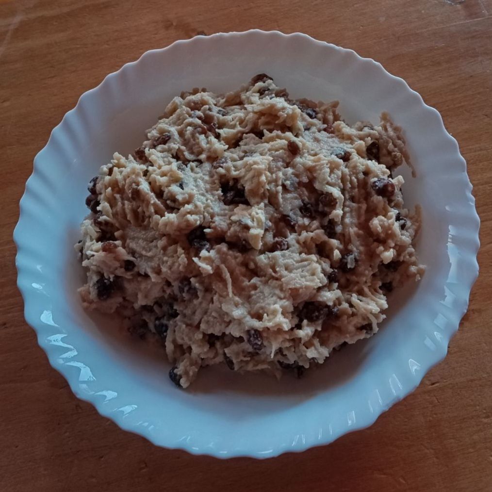 Bowl with grated apples and soaked raisins mixed with sugar, cinnamon, breadcrumbs, and sour cream for apple raisin strudel filling.