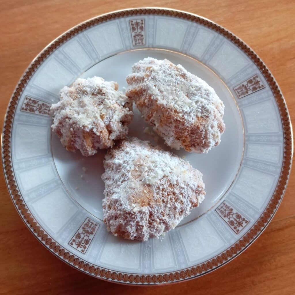 Three soft walnut sugar cookies in different shapes on a plate, baked together in various molds.