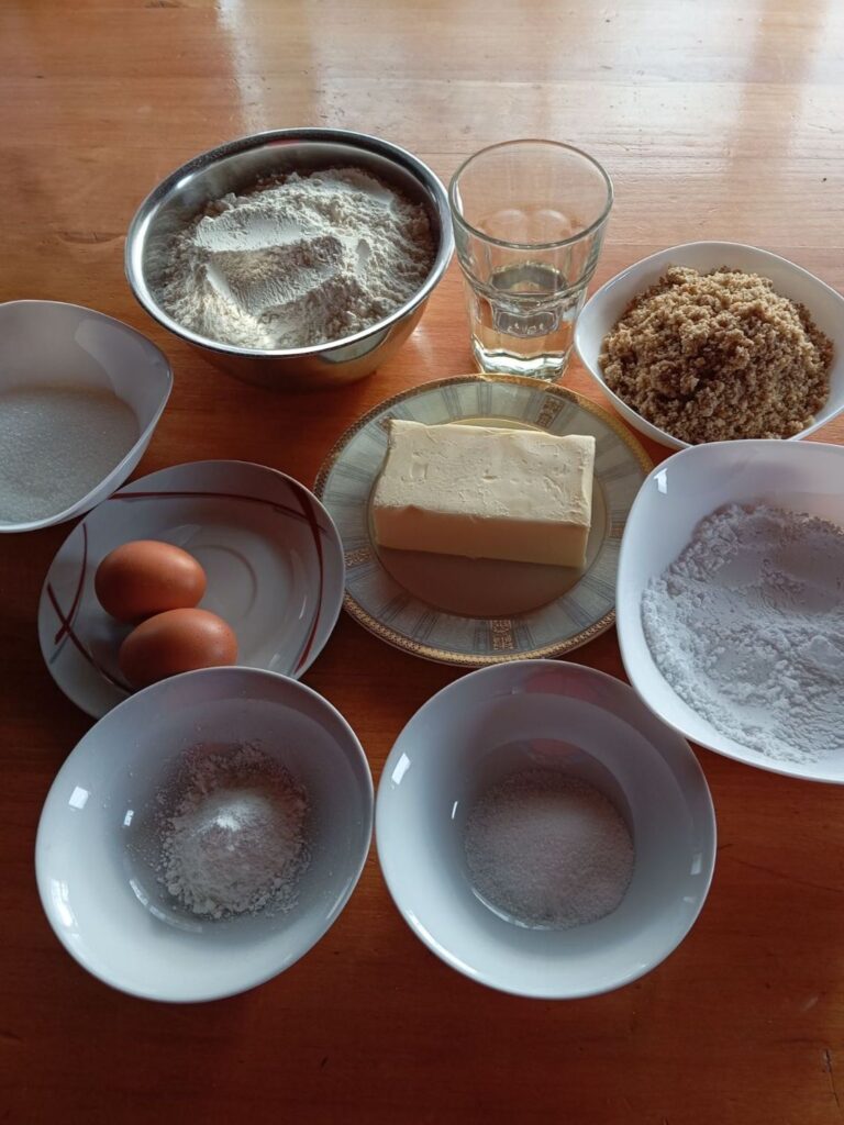 All ingredients arranged on the table: flour, ground walnuts, butter, sugar, eggs, oil, and vanilla sugar.
