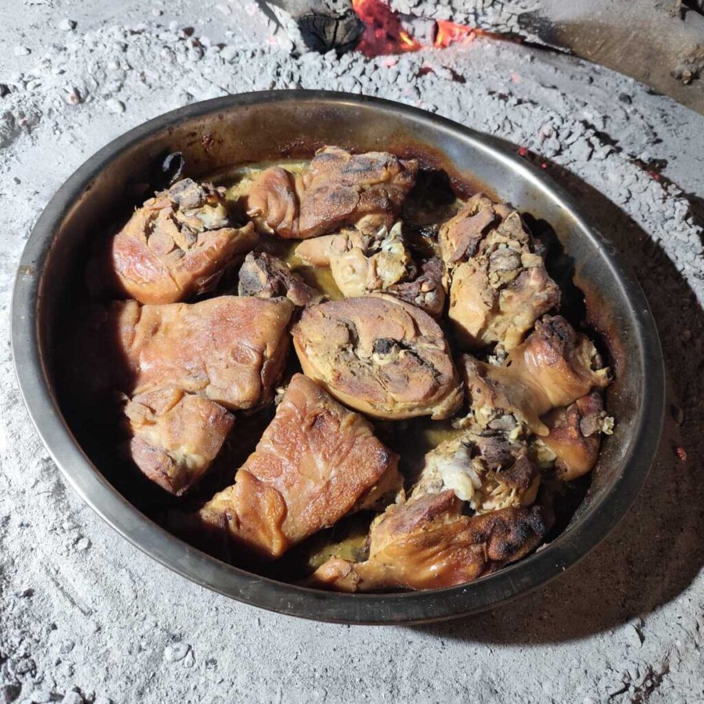 Suckling Pig Peka Style in a round pan, freshly roasted and uncovered, showing tender meat and natural juices.