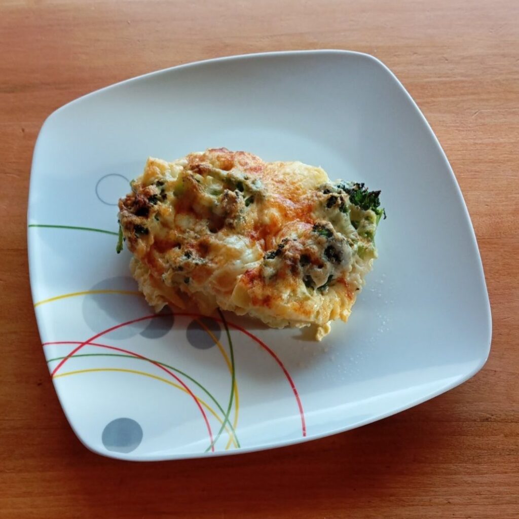 Served slice of Vegetable Egg Cheese Moussaka placed on a flat plate, showing a baked vegetable and cheese texture ready to enjoy.