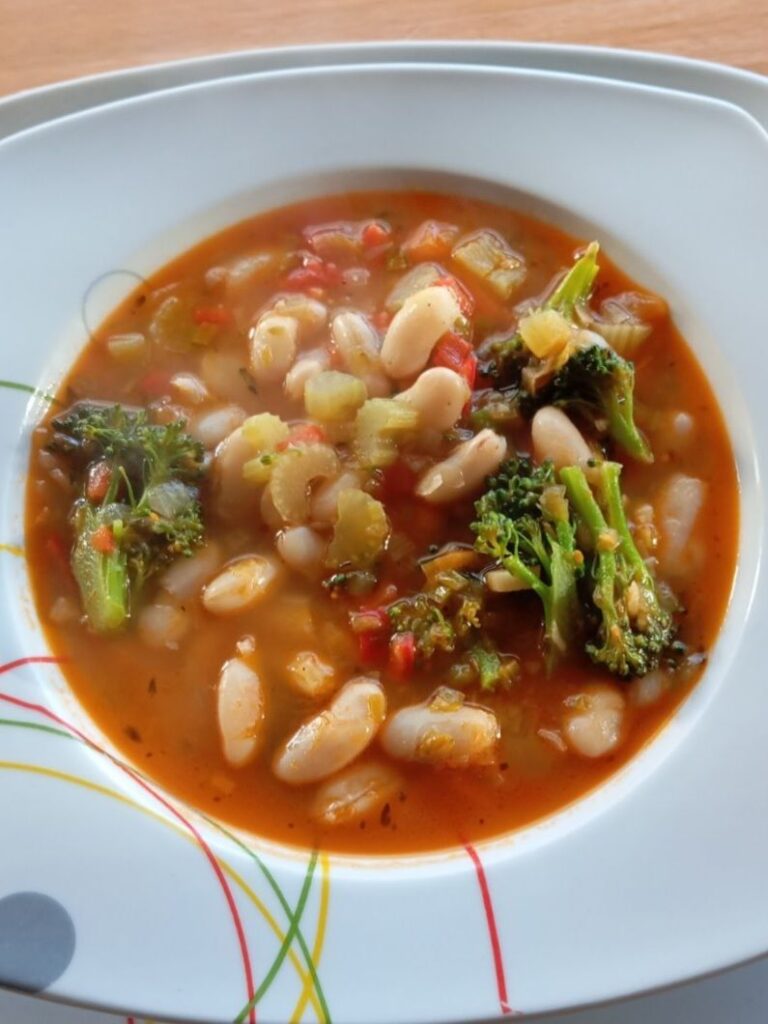 Close-up of a served deep plate of Hearty Vegetable Bean Soup with visible vegetables and beans.