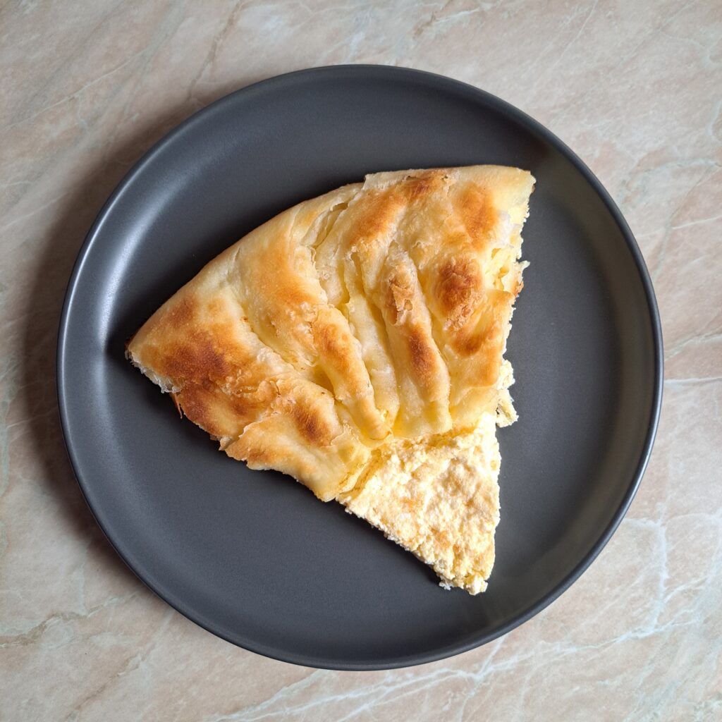 Served slice of Cheese Egg Ring Pie on a plate, showing golden crust and soft cheese egg filling in the center.