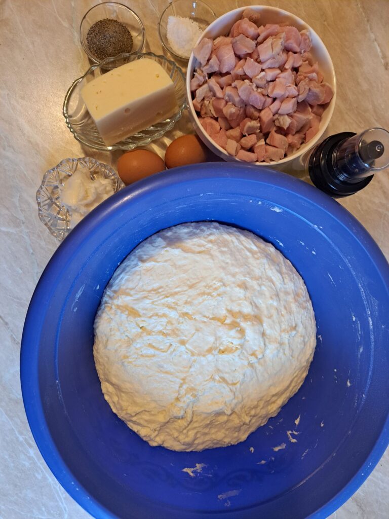 Prepared dough alongside pork loin, cheese, eggs, pork lard, salt, black pepper, and cooking oil arranged for Homemade Cheesy Pork Pastrmajlija.