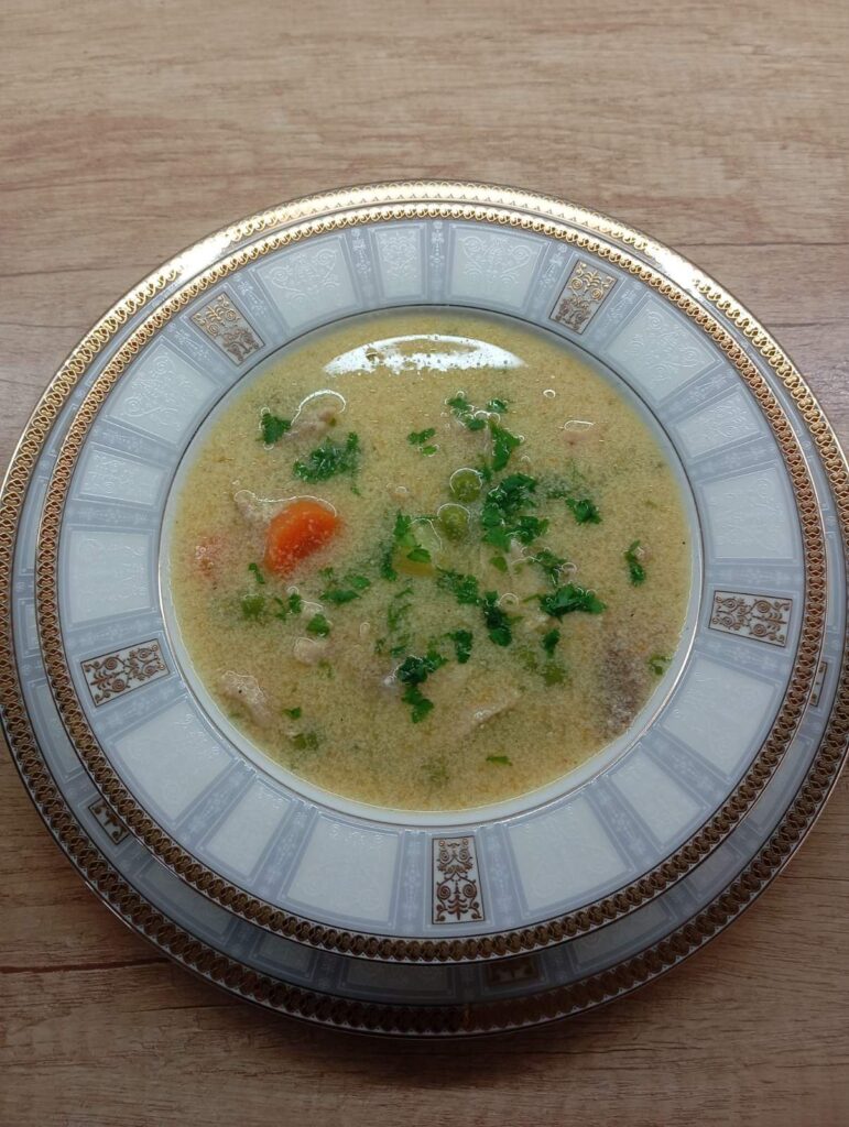 Creamy White Chicken Soup in a deep wide plate, showing tender chicken, soft vegetables, smooth broth, and fresh parsley garnish.