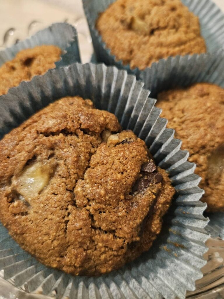 Glass bowl filled with homemade chocolate banana oat muffins in paper cups.
