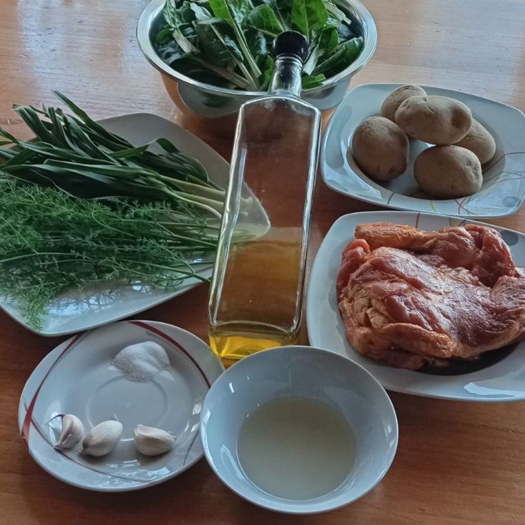 Fresh ingredients for pork chops with potatoes and chard arranged on a kitchen table before cooking.