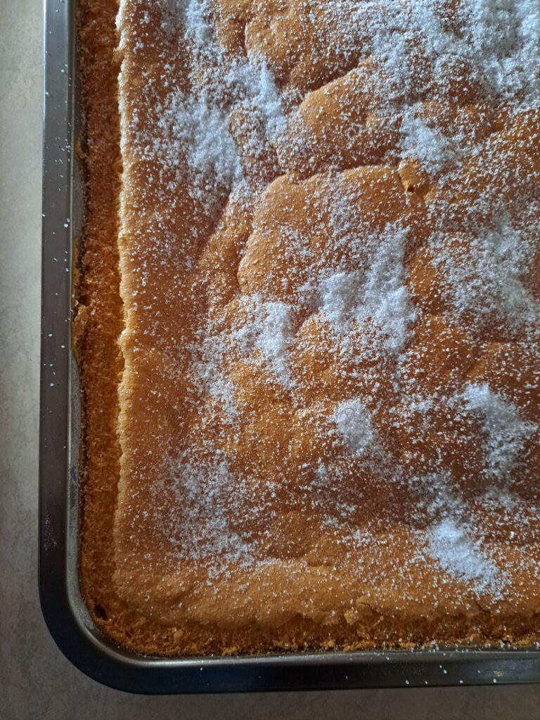 Freshly baked semolina cake in a rectangular pan, cooled and ready to be cut into even cubes.