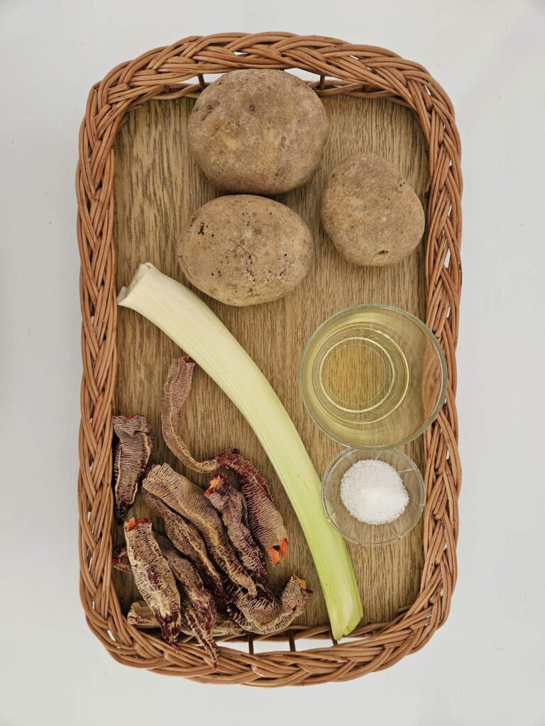 Ingredients for Dried Pepper Potato Mash including dried peppers, whole potatoes, fresh leek, oil, and salt arranged on a clean surface.