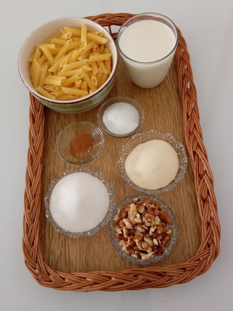 Measured ingredients for sweet milk pasta delight including pasta, milk, semolina, sugar, vanilla sugar, cinnamon, chopped walnuts, and fresh mint.